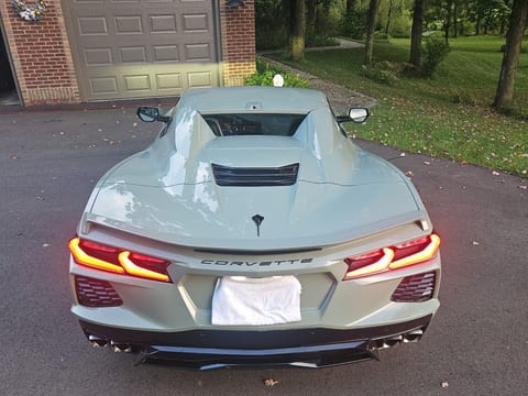 Grey-green Chevrolet Corvette photographed from behind after an exterior detail, gloss holding the reflection of the driveway