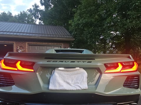 Rear of a grey-green Chevrolet Corvette after an exterior detail, tail lights lit, quad exhaust and diffuser clean