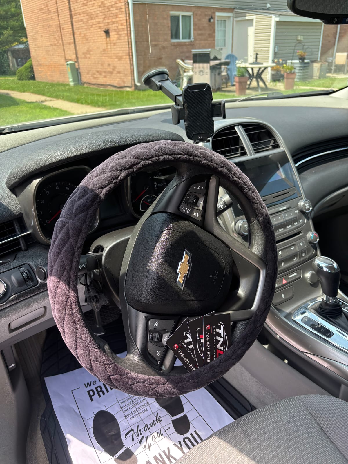 A TNL Detailing paper floor mat and business cards left in a finished Chevrolet interior