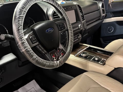 Disposable steering wheel cover in place, with a TNL Detailing paper floor mat and business cards left on the seat of a finished Ford Expedition