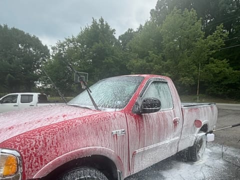 Red Ford F-150 covered in snow foam during an exterior hand wash