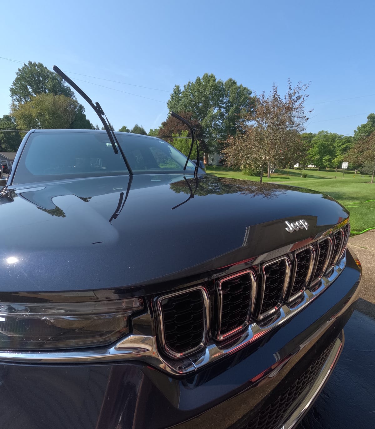 Hood and grille of a dark blue Jeep Grand Cherokee after an exterior hand wash