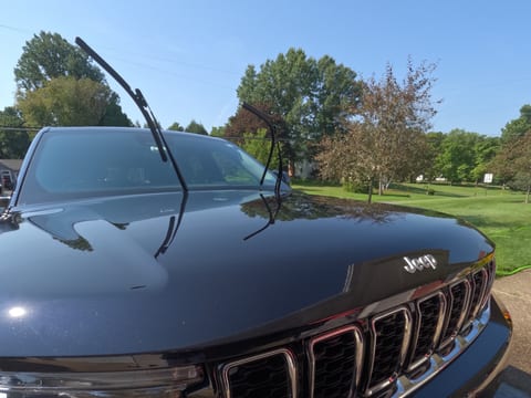 Hood and grille of a dark blue Jeep Grand Cherokee after an exterior hand wash