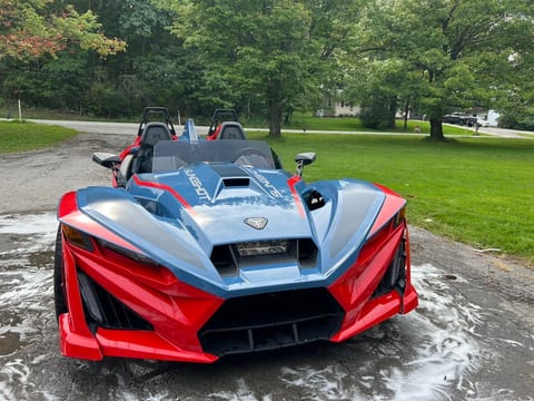 Red and blue Polaris Slingshot photographed head-on after an exterior hand wash, front fascia and headlights clean